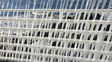 breaking waves viewed through icicles on a boardwalk railing