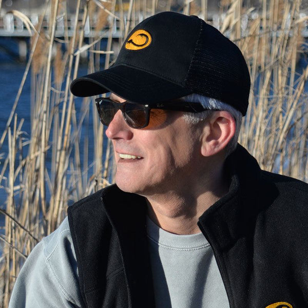 man in black Anglers Pride Tugboat Trucker fishing cap by Hook Life at a harbor